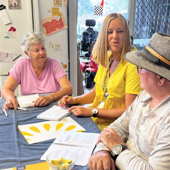 Care manager talking to two clients at their dining table