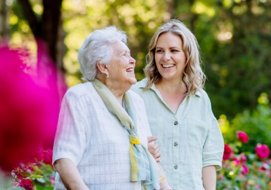 Adult daughter smiling and laughing with her mother in a rose garden