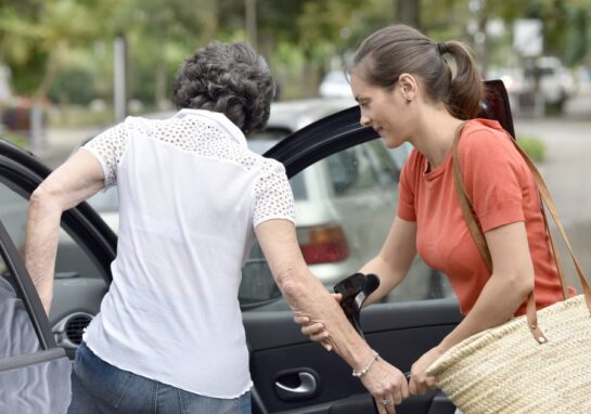 Care provider assisting their client to get in their car