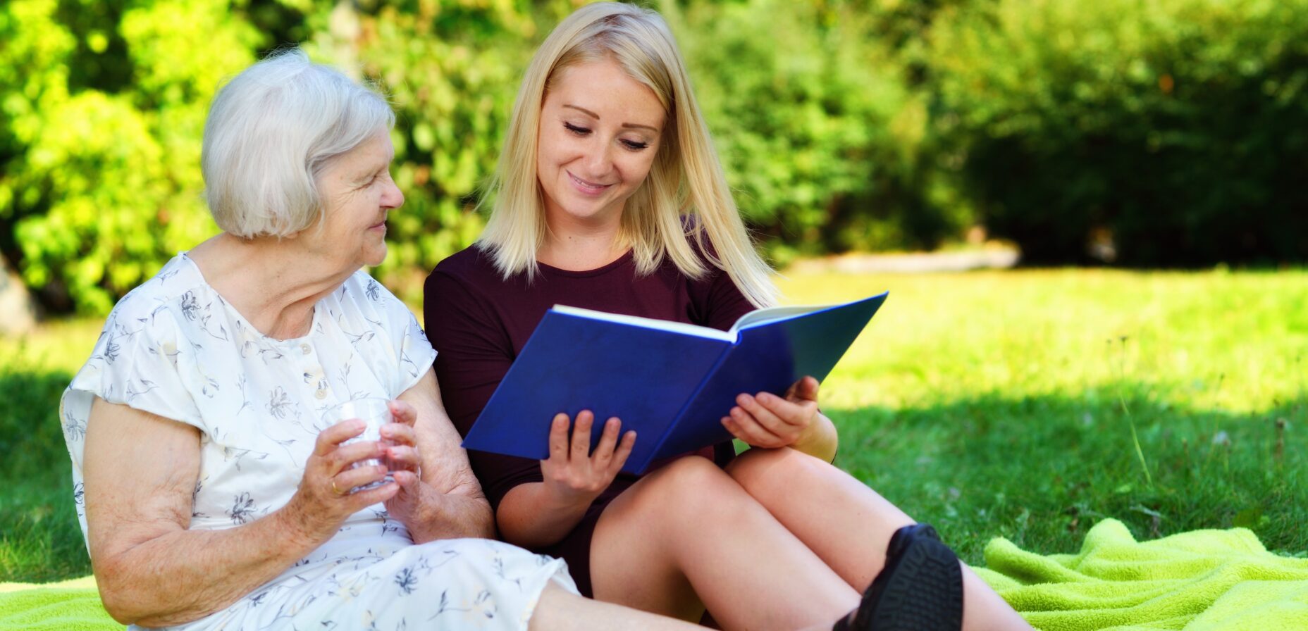 Young woman and an older woman, reading a book in the park