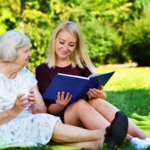 Young woman and an older woman, reading a book in the park